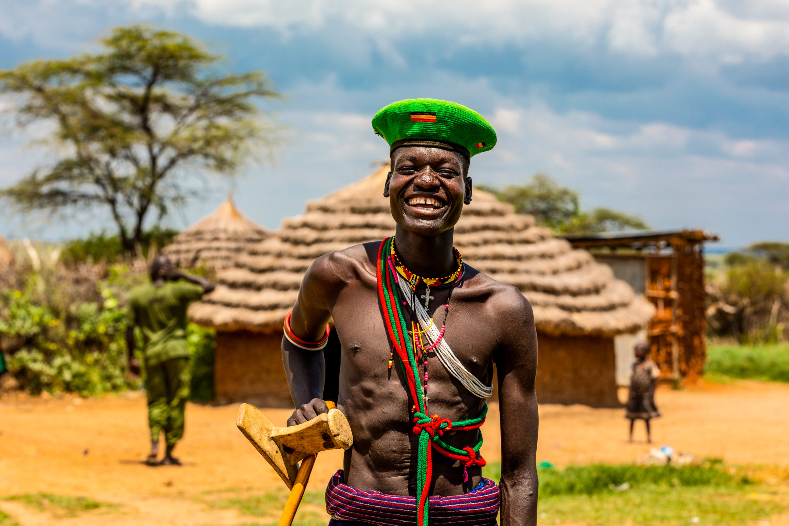 Un habitant du nord de l’Ouganda souriant devant les habitations